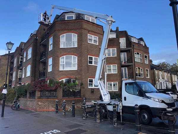 a white truck with a crane in front of a building