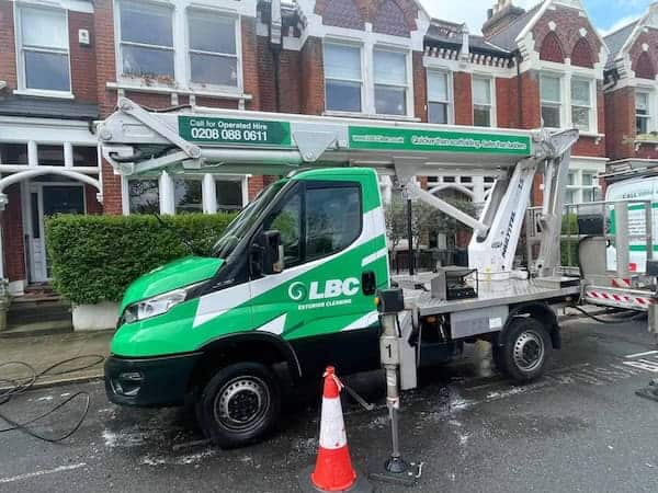 a green truck with a crane on the back parked on the street
